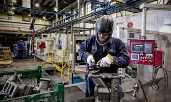 Waupaca Foundry employee inspects iron castings as they make their way through the mill room